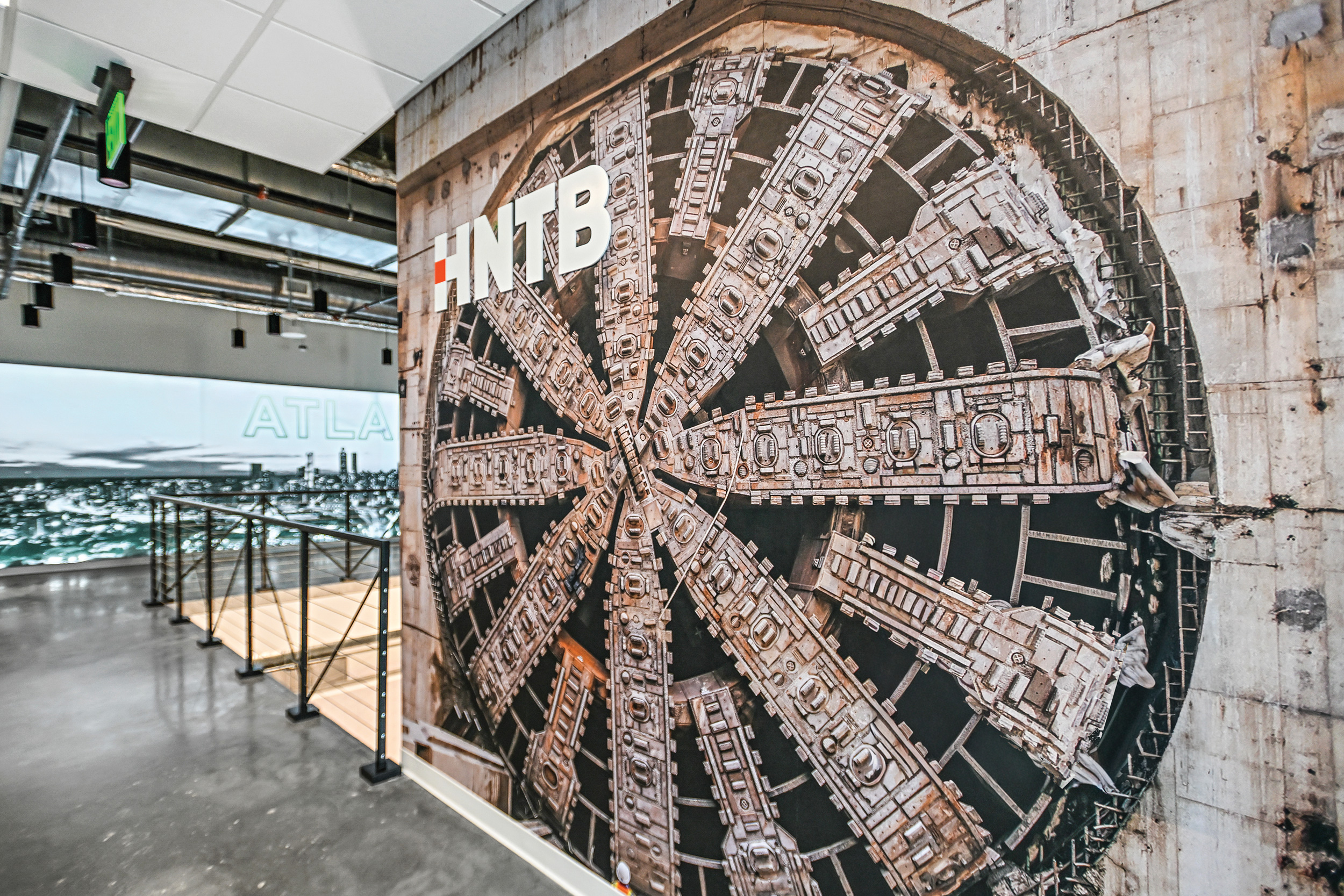 A large wallcovering with printed photo of a tunnel boring machine installed in a workplace setting.